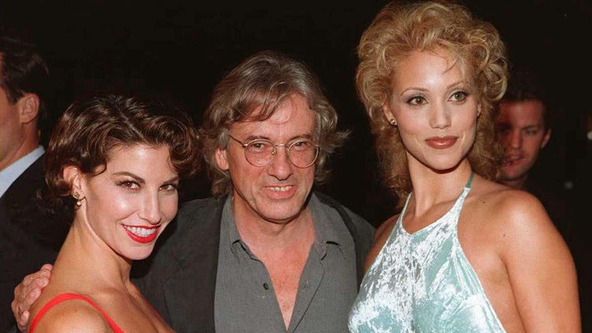 Paul Verhoeven smiling with Gina Gershon and Elizabeth Berkley at the premiere for "Showgirls."