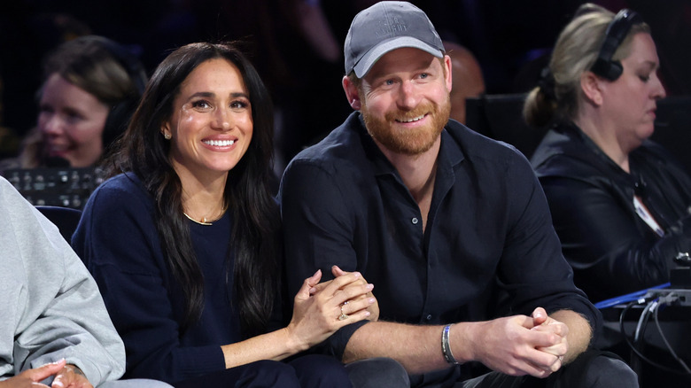 A smiling Prince Harry and Meghan Markle smiling while seated next to each other
