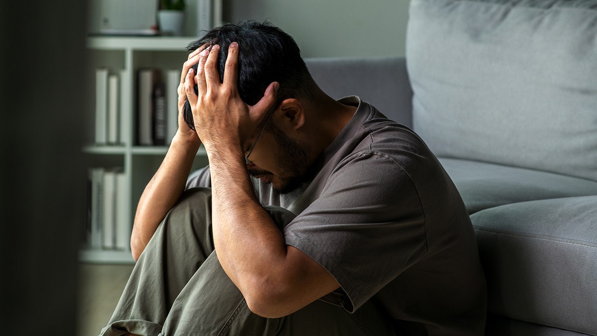 man sits on the floor with head in hands