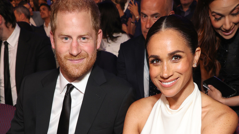Prince Harry and Meghan Markle smiling for the camera while attending an event