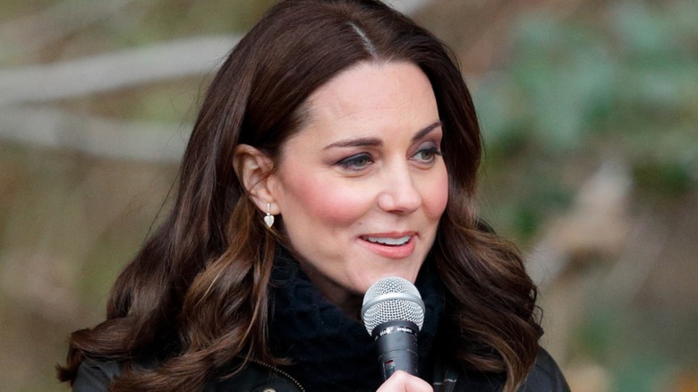 Kate Middleton speaking into a microphone while wearing a dark coat