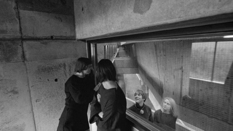 Two people looking through a window at two others in Stereo