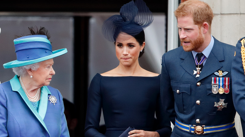 Queen Elizabeth II, Meghan, Duchess of Sussex and Prince Harry, Duke of Sussex watch a flypast to mark the centenary of the Royal Air Force from the balcony of Buckingham Palace (2018)