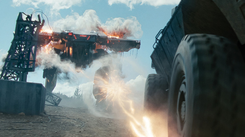 An alien mecha chases a military vehicle in War Machine
