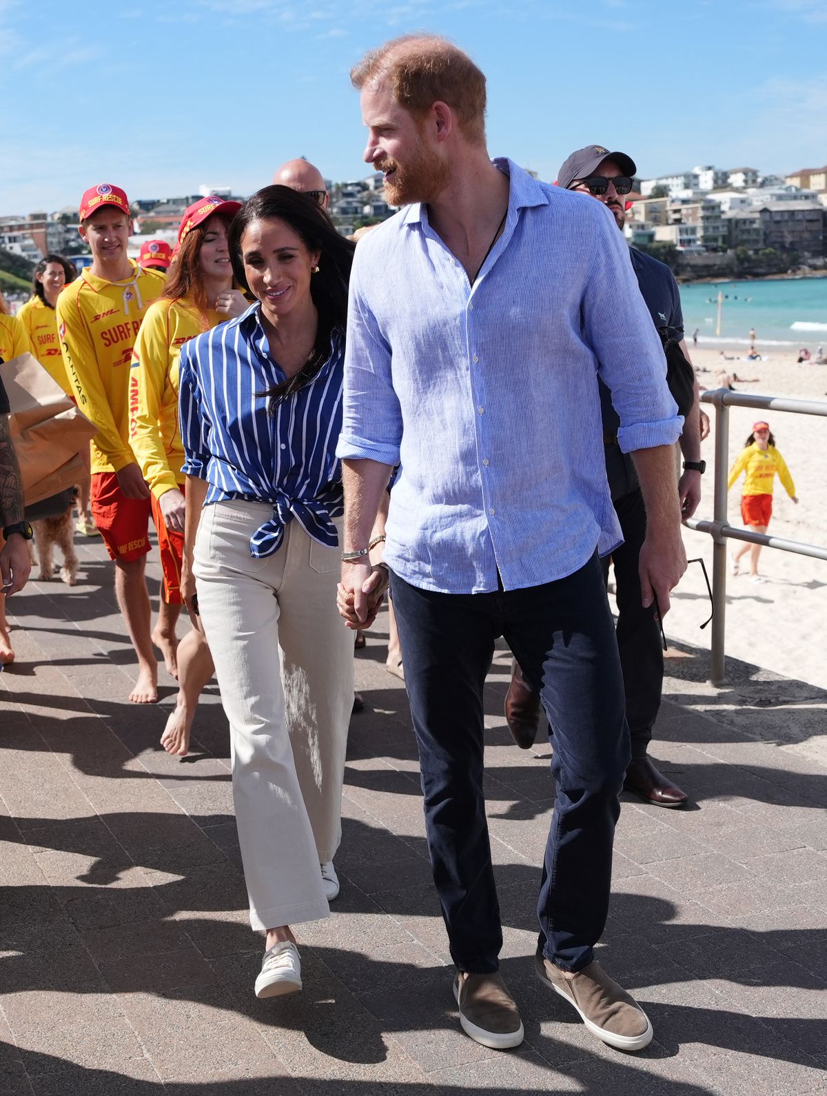 Meghan, Duchess of Sussex and Prince Harry, Duke of Sussex walk along the boardwalk after meeting volunteer first responders from Bondi Surf Bathers' Life Saving Club