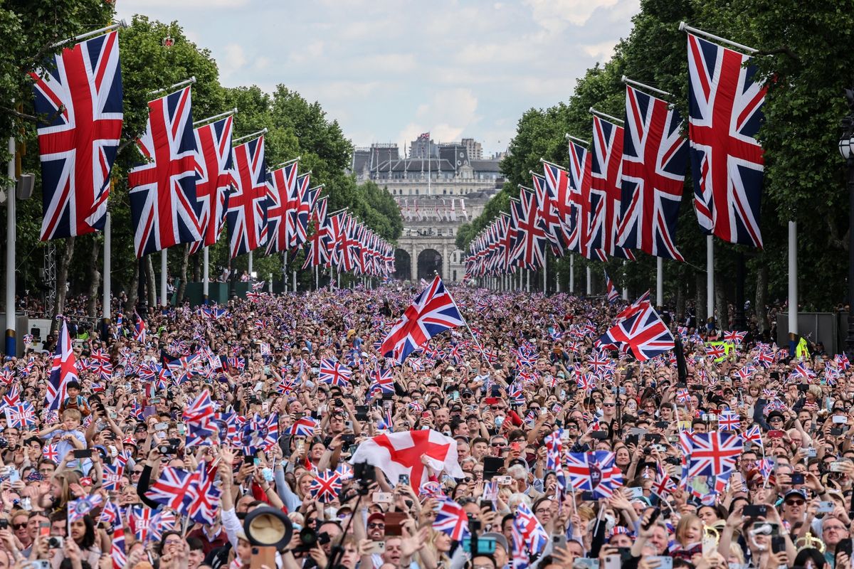 Thousands of people line The Mall outside Buckingham Palace waving Union Flags 