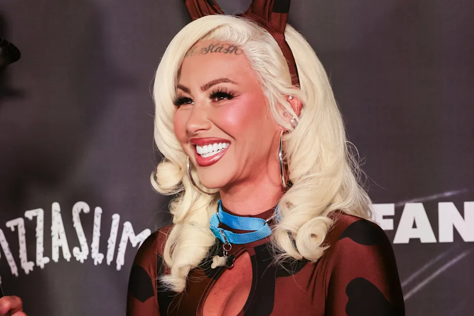 Amber Rose smiling, wearing a sheer outfit with furry accents and animal-themed headband