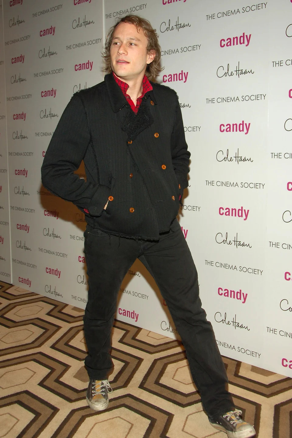 Heath Ledger in casual jacket and pants, standing at a Cinema Society event backdrop with logos