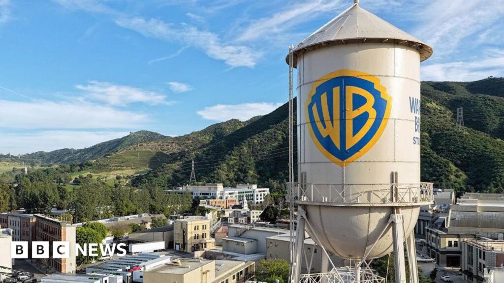 Two people silhouetted while standing and looking at the Hollywood sign