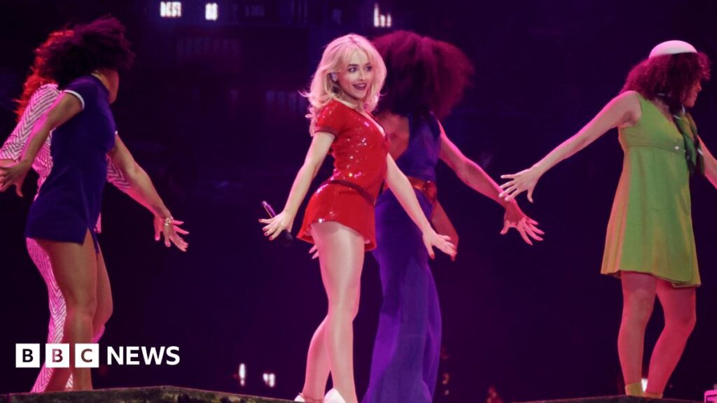 Coachella 2026: Festival kicks off with Sabrina Carpenter and surprise guests Sabrina Carpenter performs at the Coachella Stage wearing a red dress and white heels. She is surrounded by female dancers.