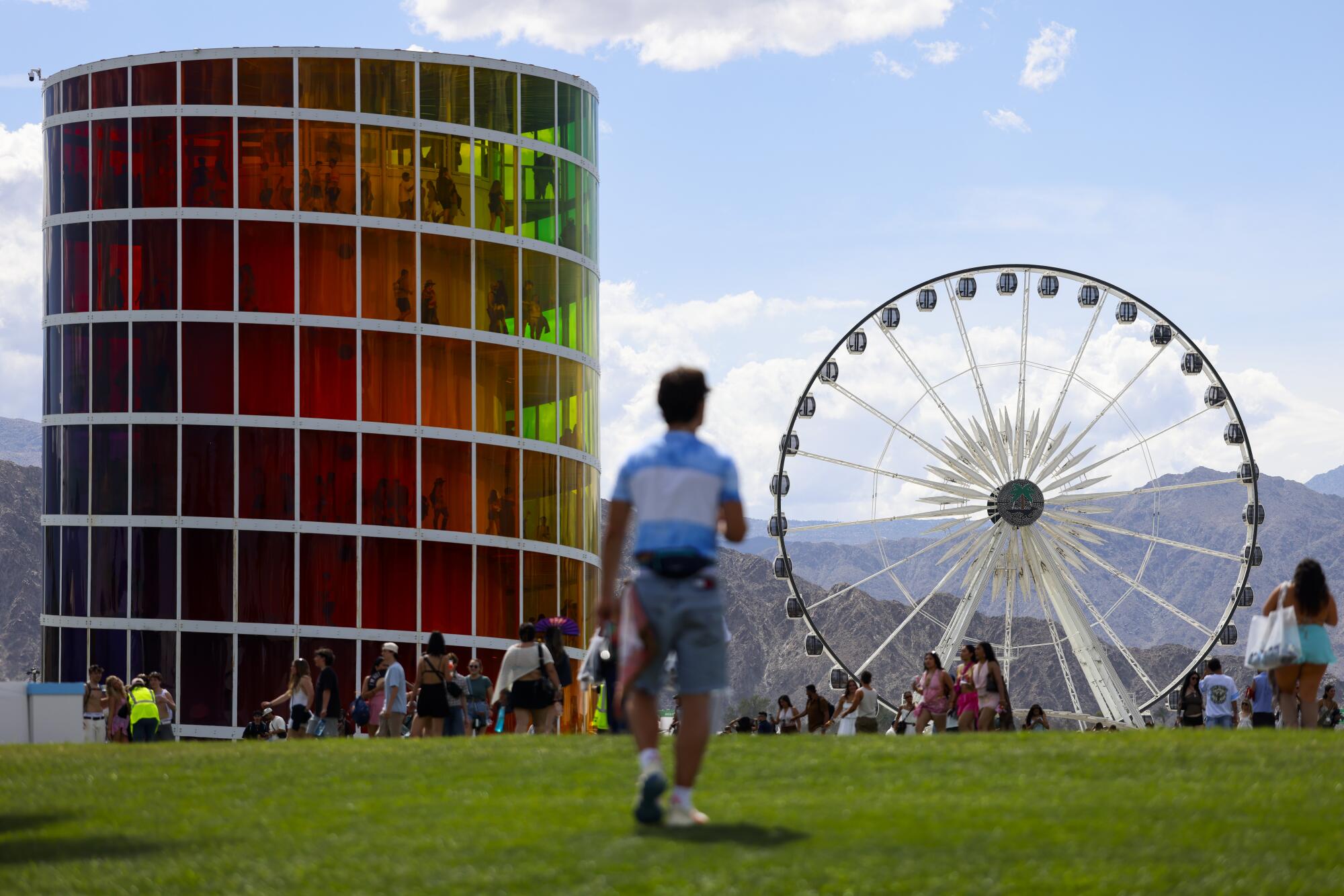 Festival goers walk near the SPECTRA multicolored and multi-tiered structure and a Ferris Wheel.