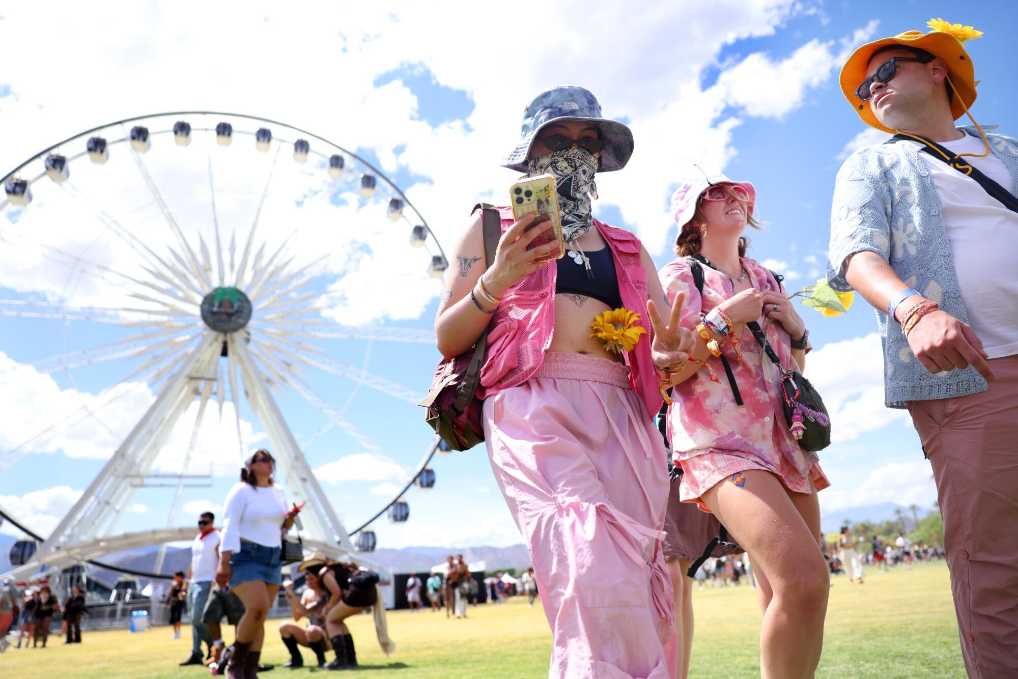 People walk the grounds at Coachella with a Ferris wheel in the background