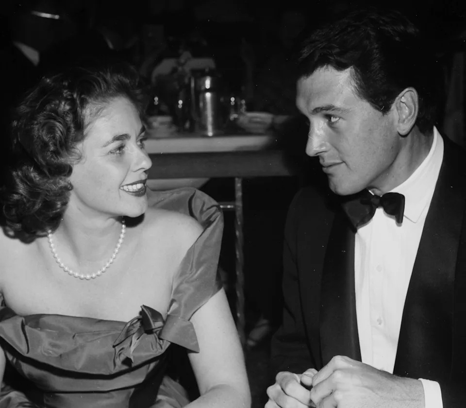 Rock Hudson and Phyllis Gates seated at a formal event, wearing elegant evening attire