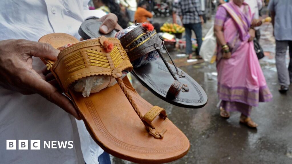A shopkeeper holds Kolhapuri sandals, a traditional Indian style of footwear, at a roadside shop in Mumbai, India, on July 4, 2025.