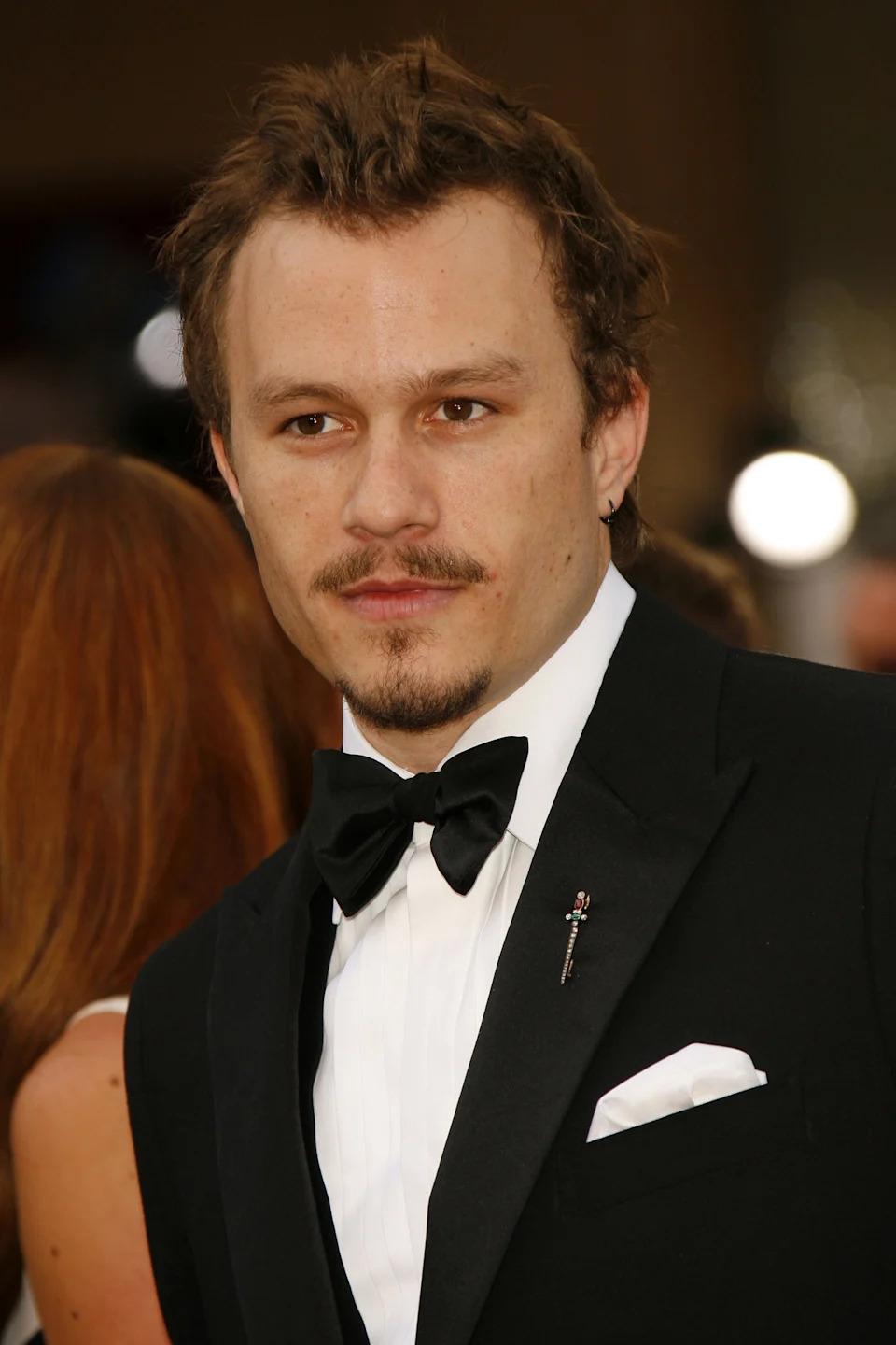 Heath Ledger in formal suit and bow tie at a public event, with a focused expression