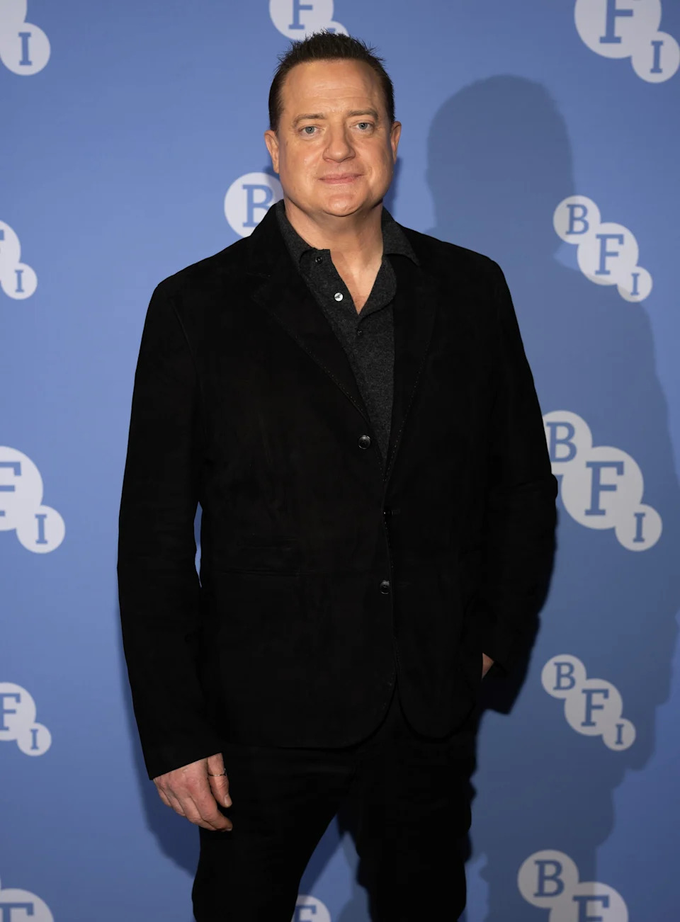Person in a dark suit stands against a backdrop with "BFI" logos, likely at a film event