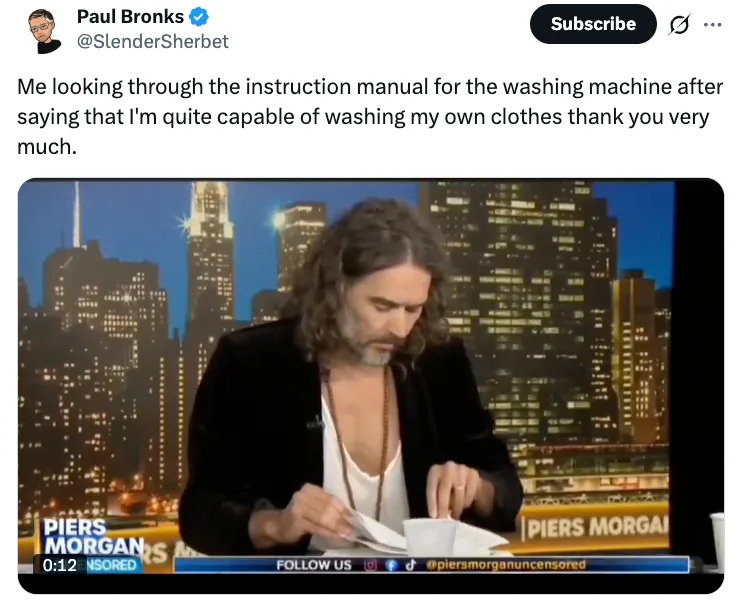 A man with long hair and a relaxed outfit looks at papers on a talk show set, with a caption joking about using a washing machine manual