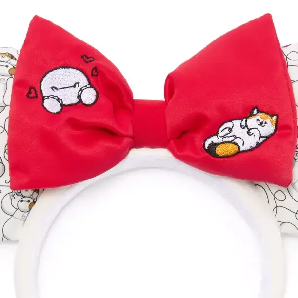 The red bow is embroidered with a happy Baymax surrounded by hearts on one side and a contented Mochi rolled over and showing his belly on the other.