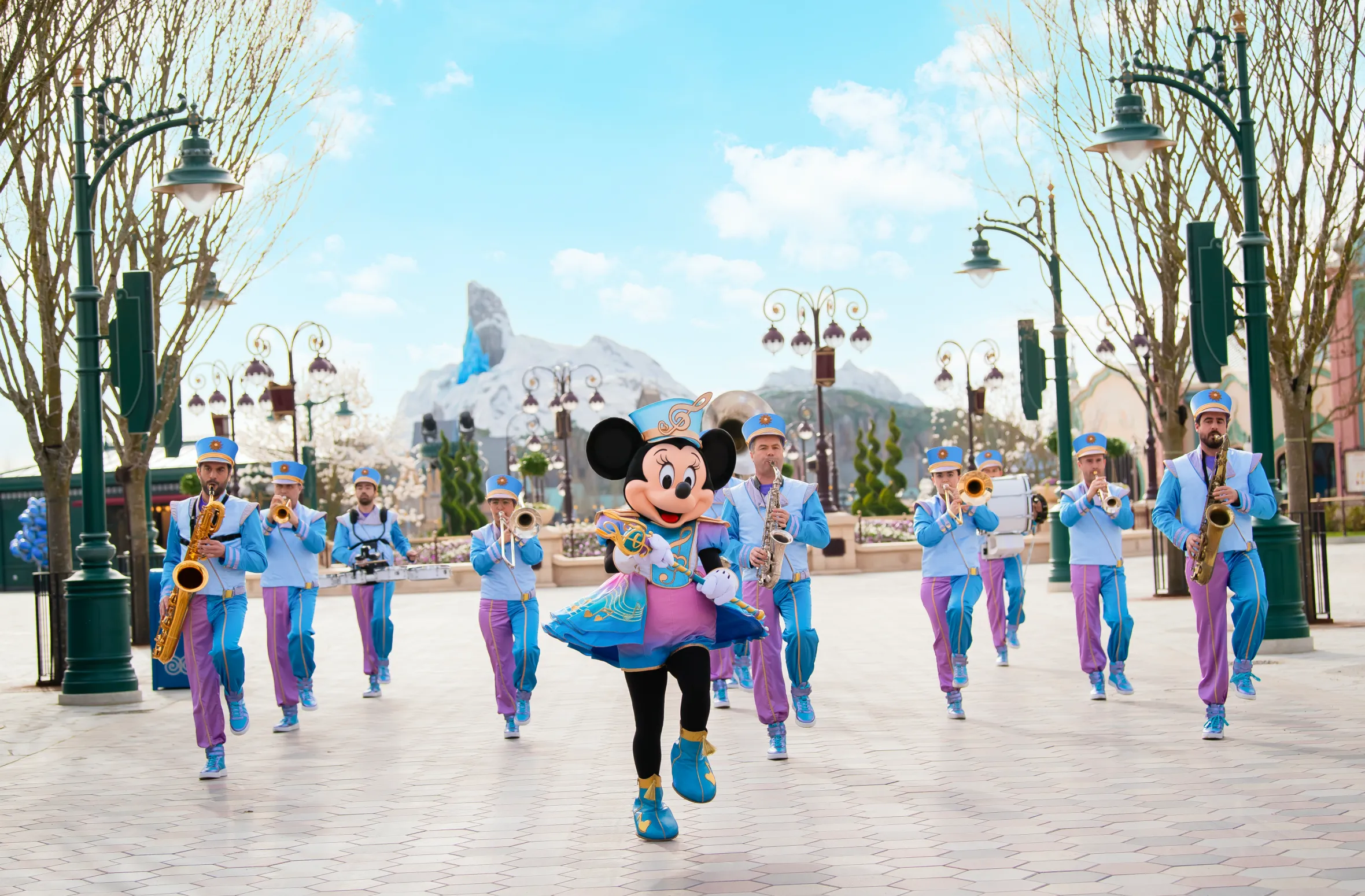 Minnie Mouse in a blue and pink marching band uniform leading the Disney Marching Band at Disneyland Paris.