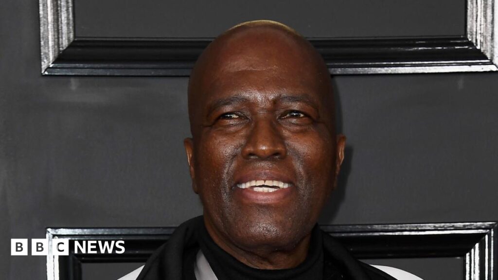 A close-up shot of Albert Mazibuko smiling with a black background behind him