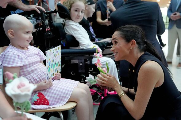 Meghan receives a card and a knitted flower from a young cancer patient