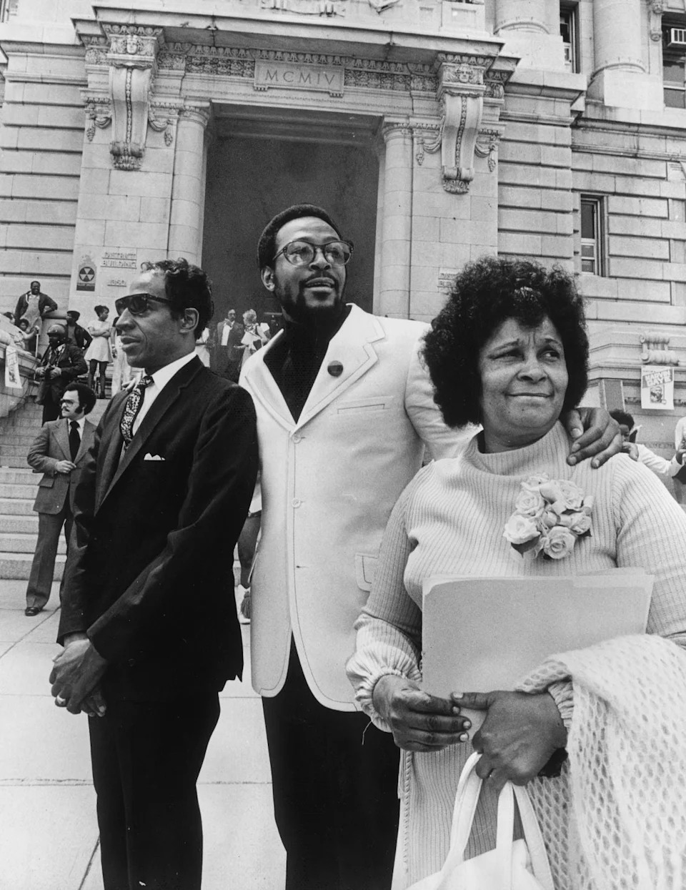 Marvin Gaye stands between his parents in front of a historic building with columns