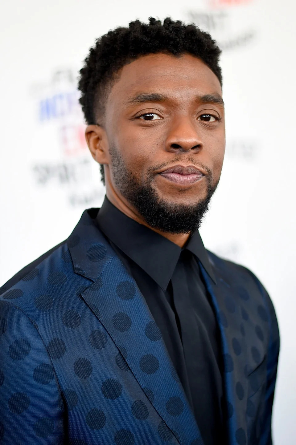 Man in a polka-dot suit on the event's red carpet, posing confidently for the camera