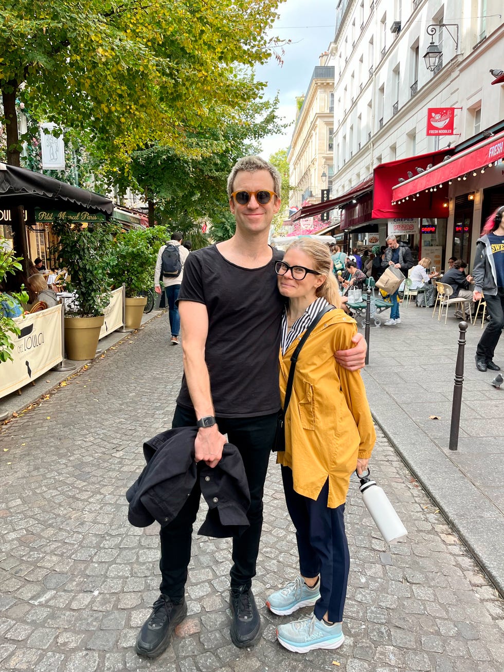 Couple posing on a street bustling with outdoor dining.