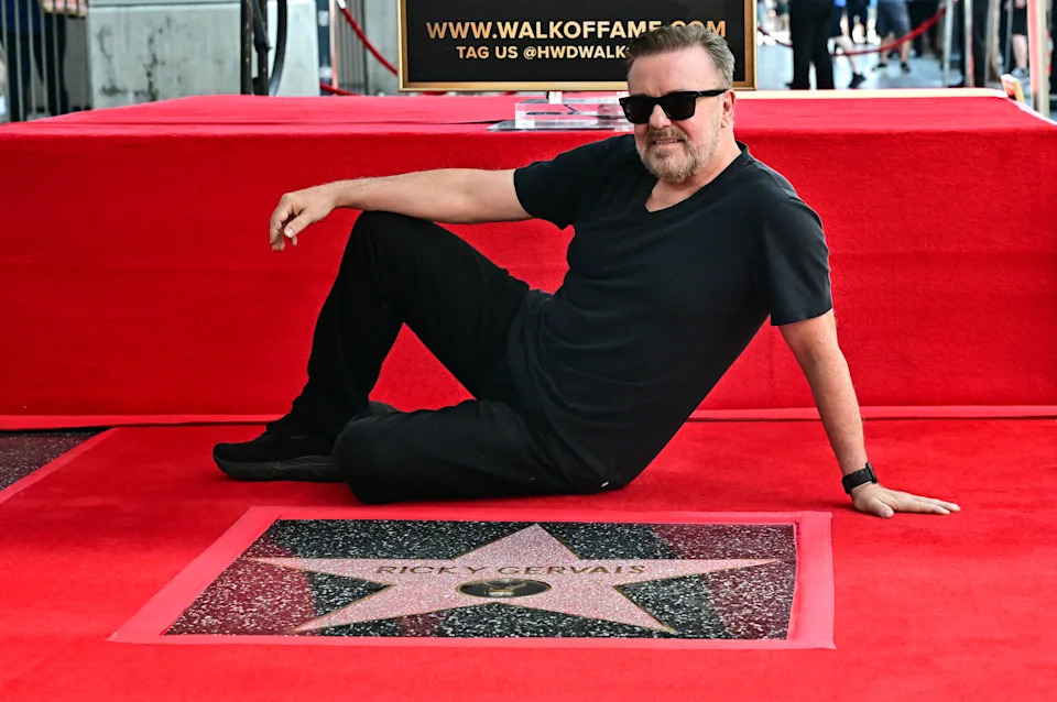 Person sitting casually on a Hollywood Walk of Fame star, wearing a black t-shirt and pants, and sunglasses