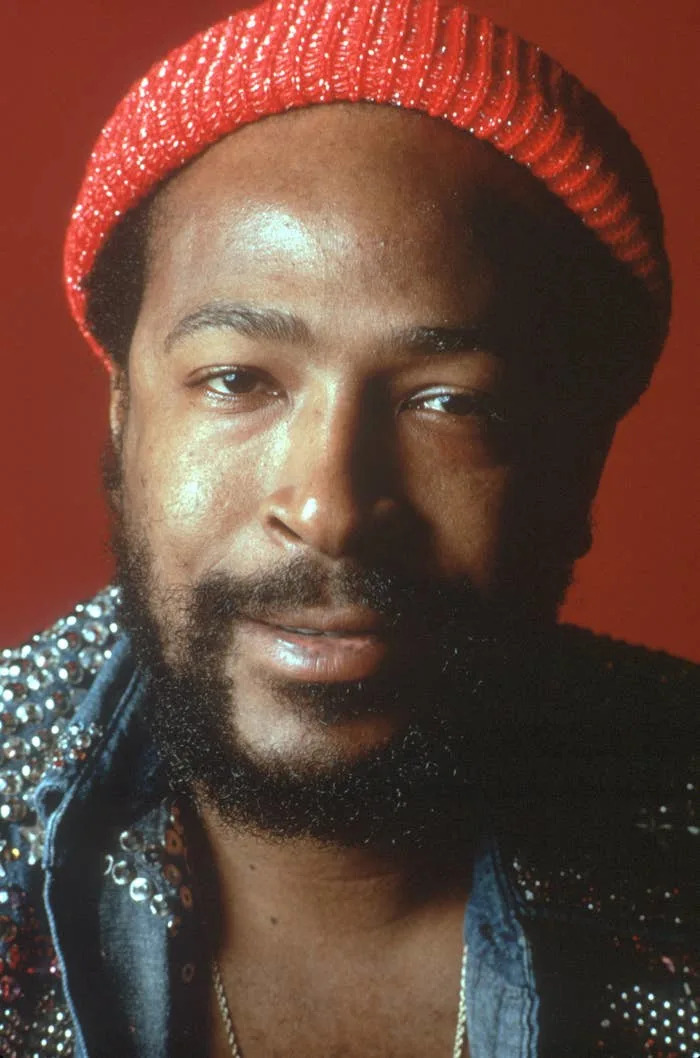 Marvin Gaye wearing a sequined jacket and knit cap, looking directly at the camera with a calm expression