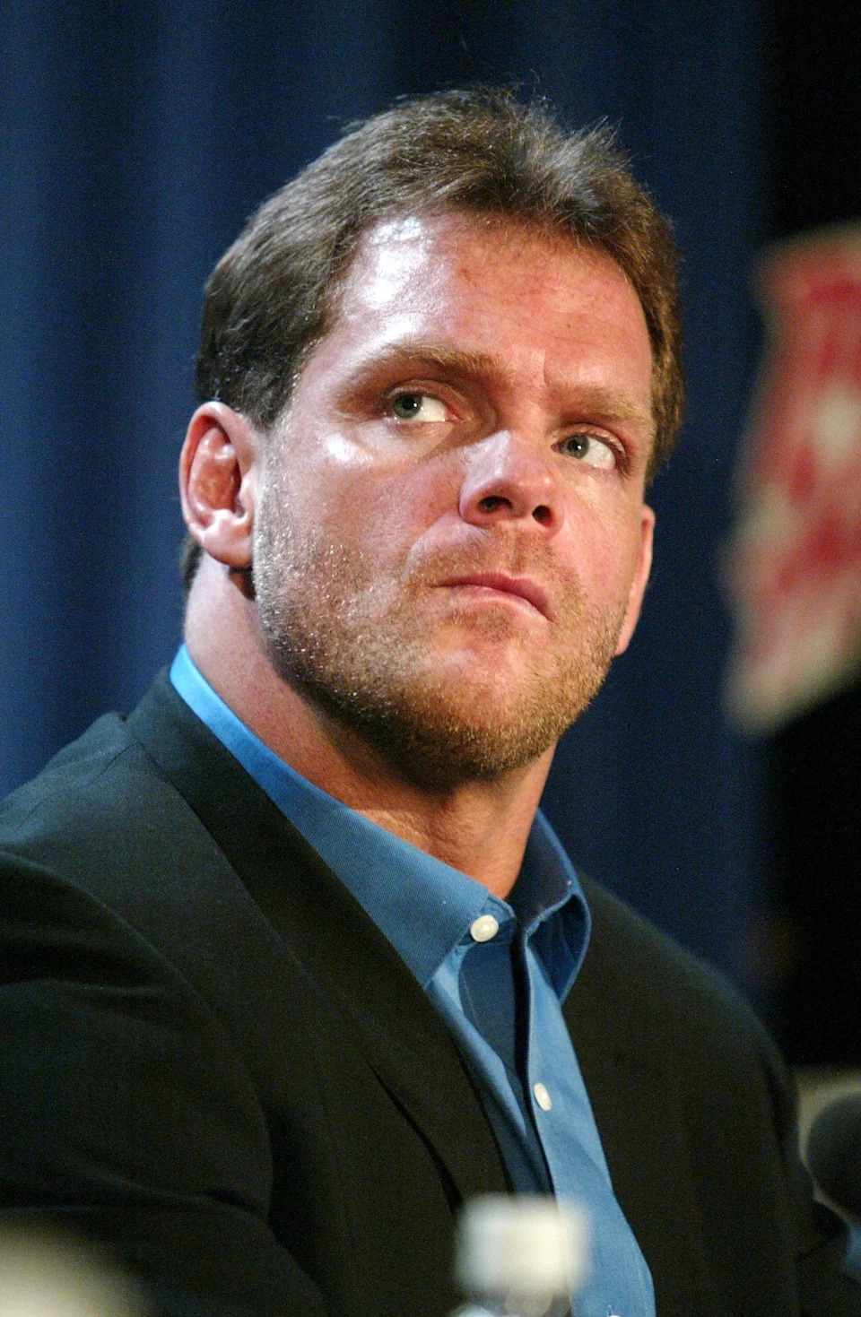 Chris Benoit in a suit looks to the side at a formal event