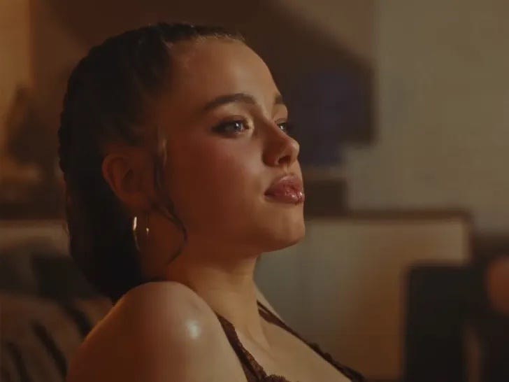 Person sitting indoors with braided hair and earrings.