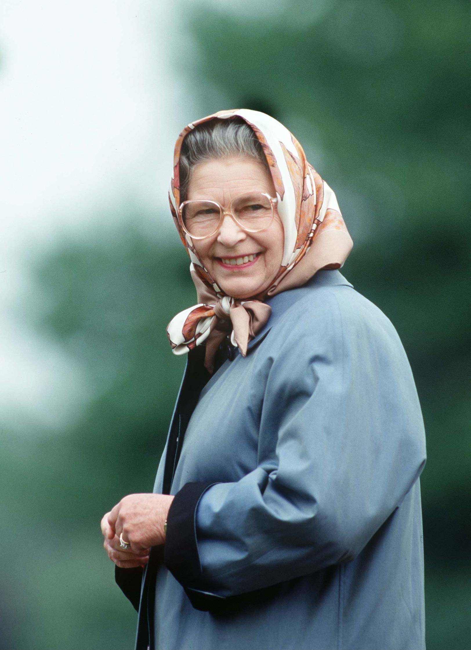 queen elizabeth wearing a jacket and headscarf with glasses