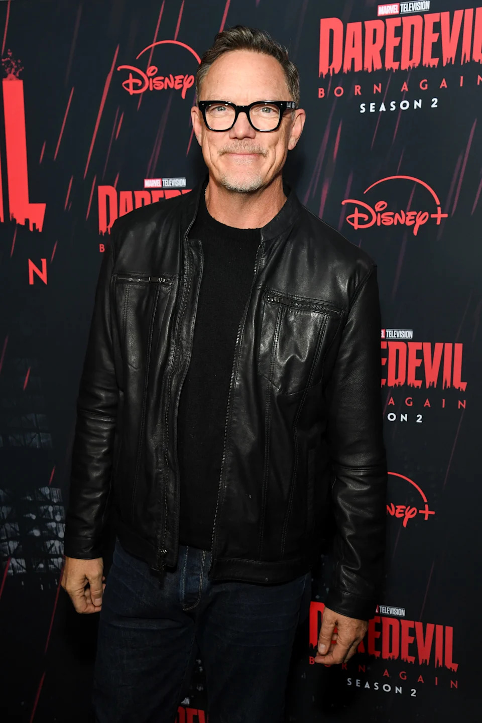 A person in a leather jacket poses on the red carpet for "Daredevil: Born Again, Season 2" event