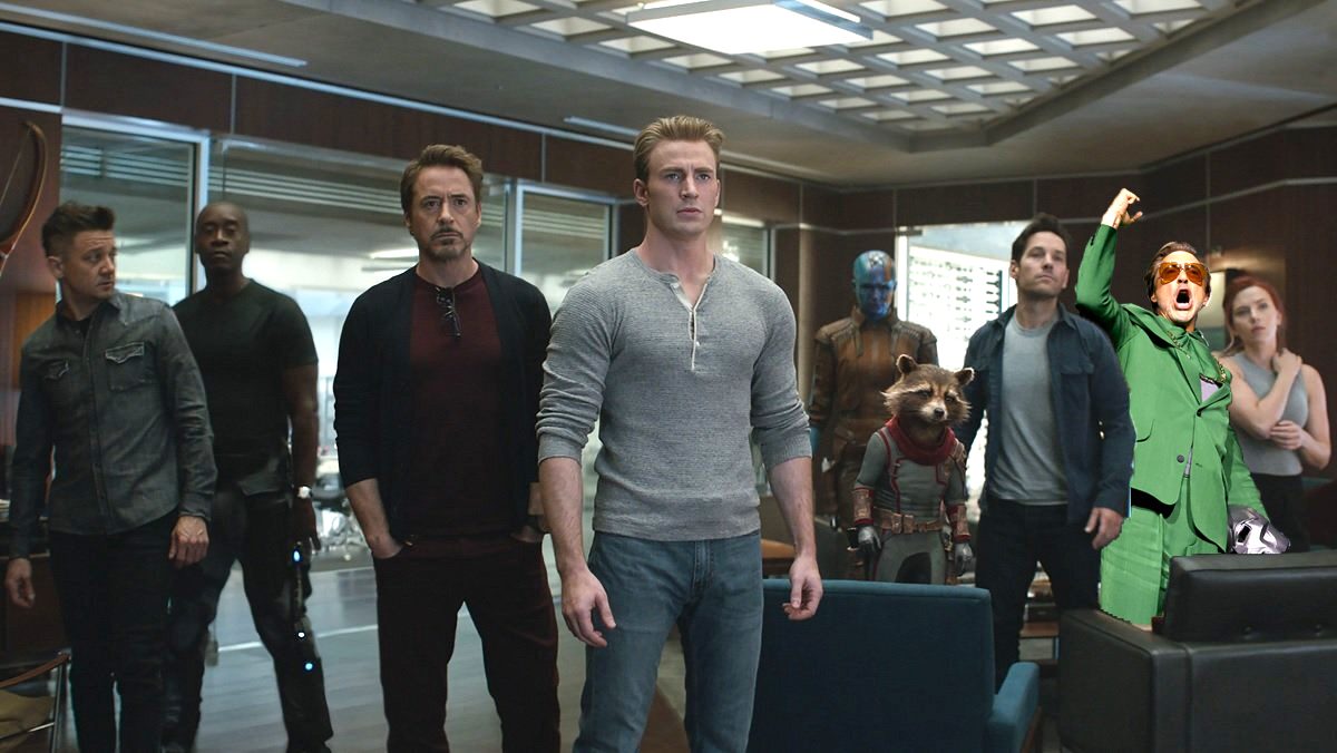 The Avengers standing in a room looking nervous with a yelling Robert Downey Jr. in a green suit photoshopped in