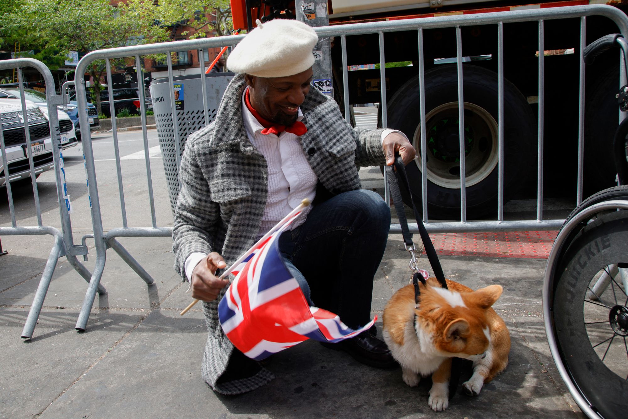 A man with a corgi holds a UK flag ahead of King Charles’ visit to Harlem