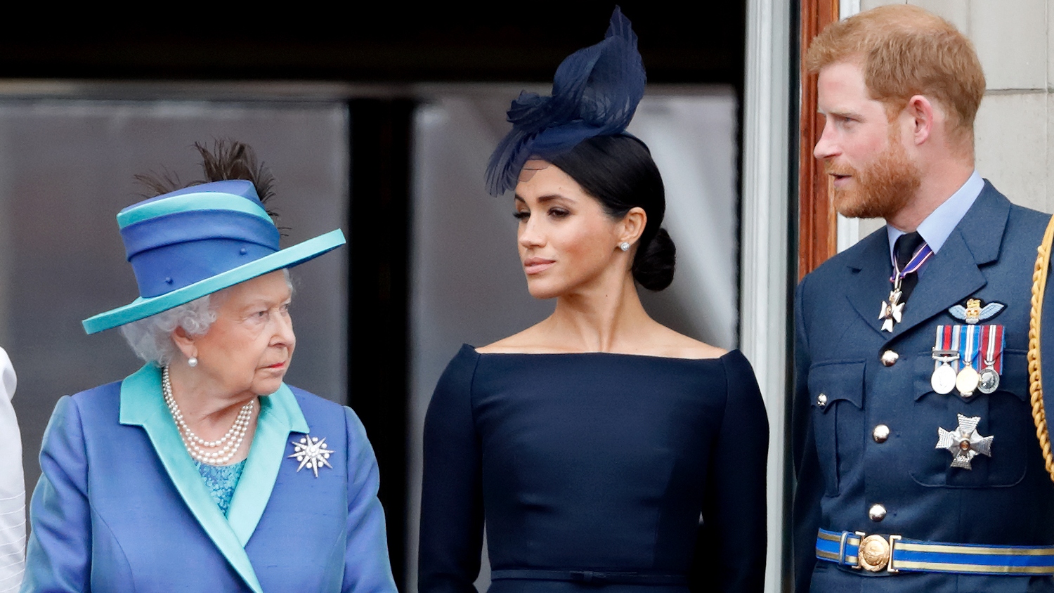 Queen Elizabeth II, Meghan, Duchess of Sussex and Prince Harry, Duke of Sussex watch a flypast to mark the centenary of the Royal Air Force