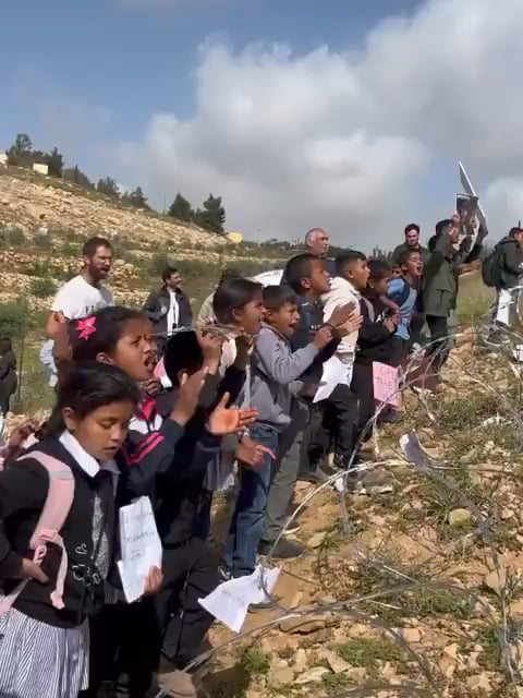 Palestinian children protest at barbed wire erected by Israeli settlers in occupied West Bank village of Um al-Khair—calling for their basic right to access their school, move freely, & live without occupation.
