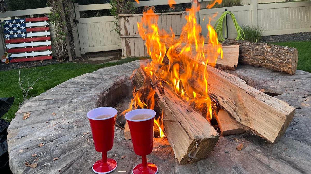 Fire pit with two red Solo cups and an American flag pallet behind the raging fire.