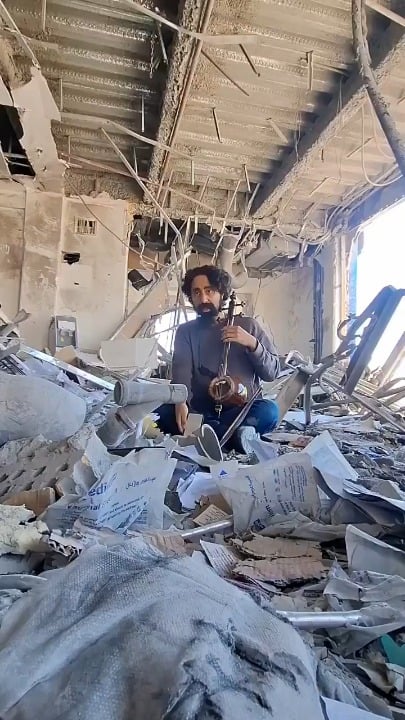 Iranian musician Hamidreza Afrideh plays at the ruins of his old music school "I want the last sound from the school not be that of missiles and war, The last sound should be music."