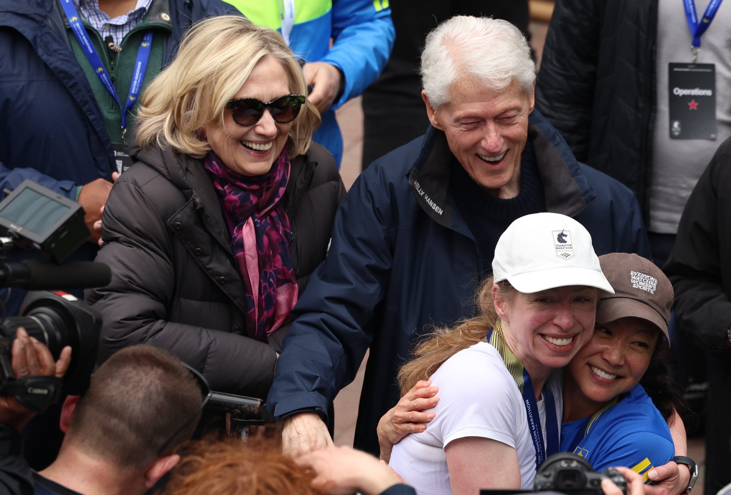 Former President Bill Clinton and his wife, former First Lady and Secretary of State Hillary Clinton, smile as their daughter Chelsea poses for a picture with her friend after the pair completed the Boston Marathon.