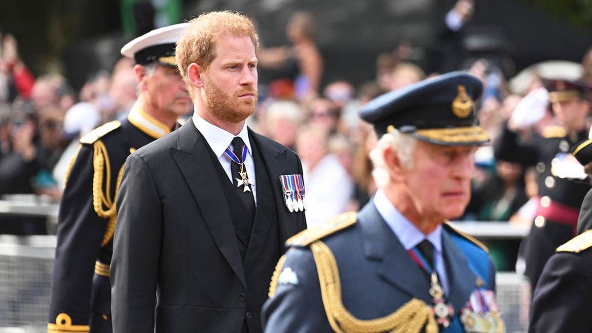 Prince Harry looking somber in a black suit walking behind his father, King Charles III, in uniform during a funeral procession for Queen Elizabeth II in London.