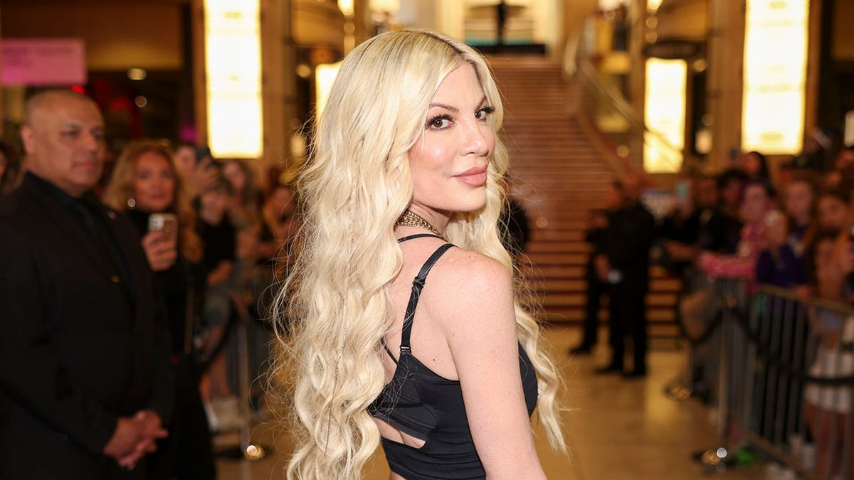 Tori Spelling standing at the 2024 iHeartRadio Music Awards backstage area.