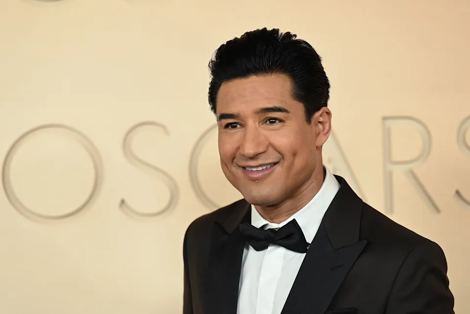 A person at a red carpet event in a classic tuxedo with a bow tie, smiling towards the camera