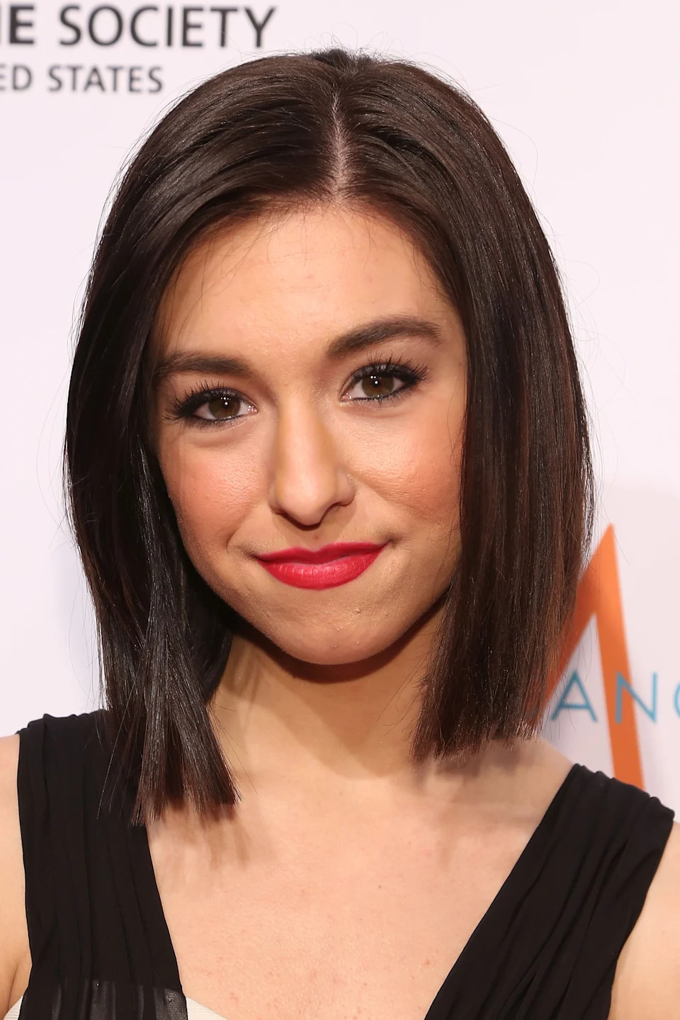 Christina Grimmie on a red carpet wearing a sleeveless dress with a sleek bob hairstyle