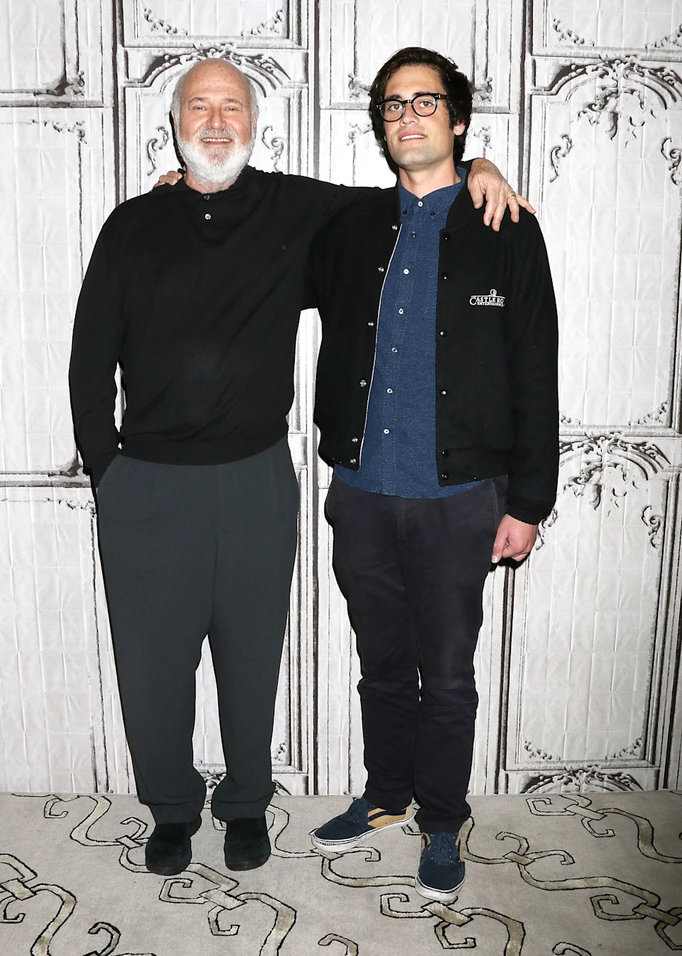 Rob Reiner smiling with an arm around Nick Reiner at an event