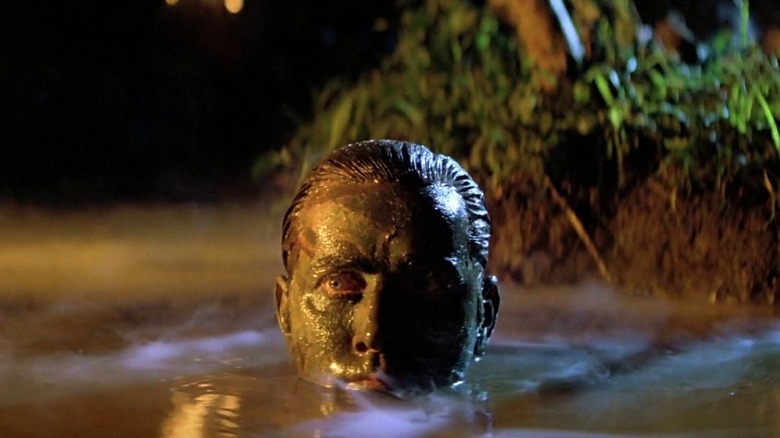 Martin Sheen as Captain Benjamin Willard in Apocalypse Now, covered in mud as he raises his head out from the water of a grotto.