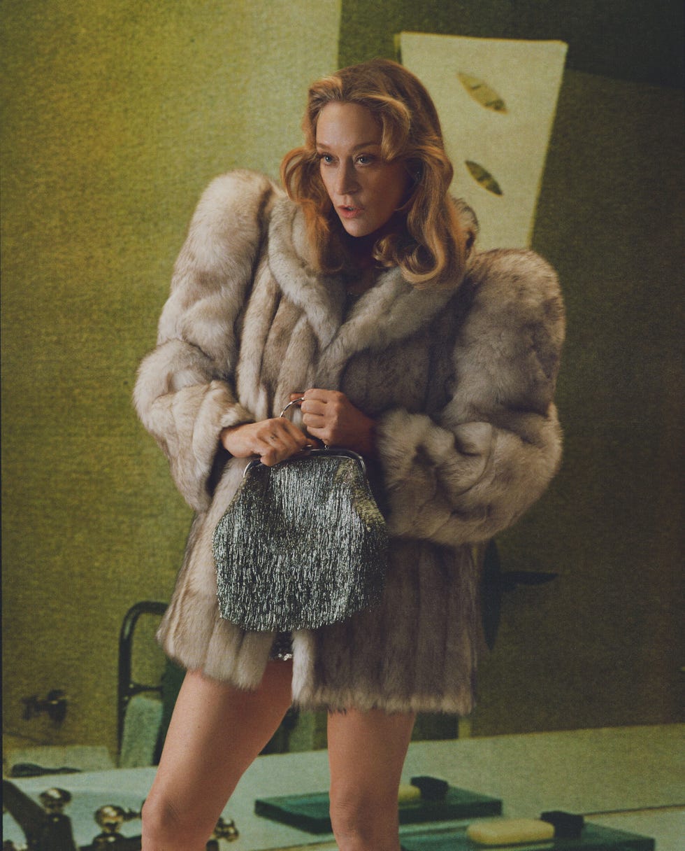 Model wearing a fur coat and holding a sparkly handbag.