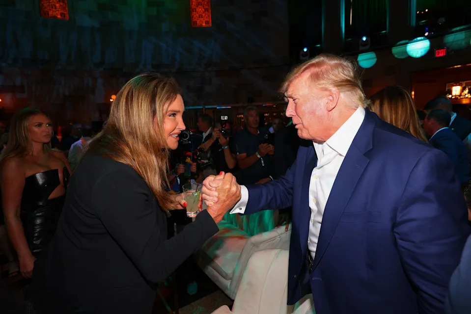 Caitlyn Jenner and Donald Trump shake hands surrounded by other people