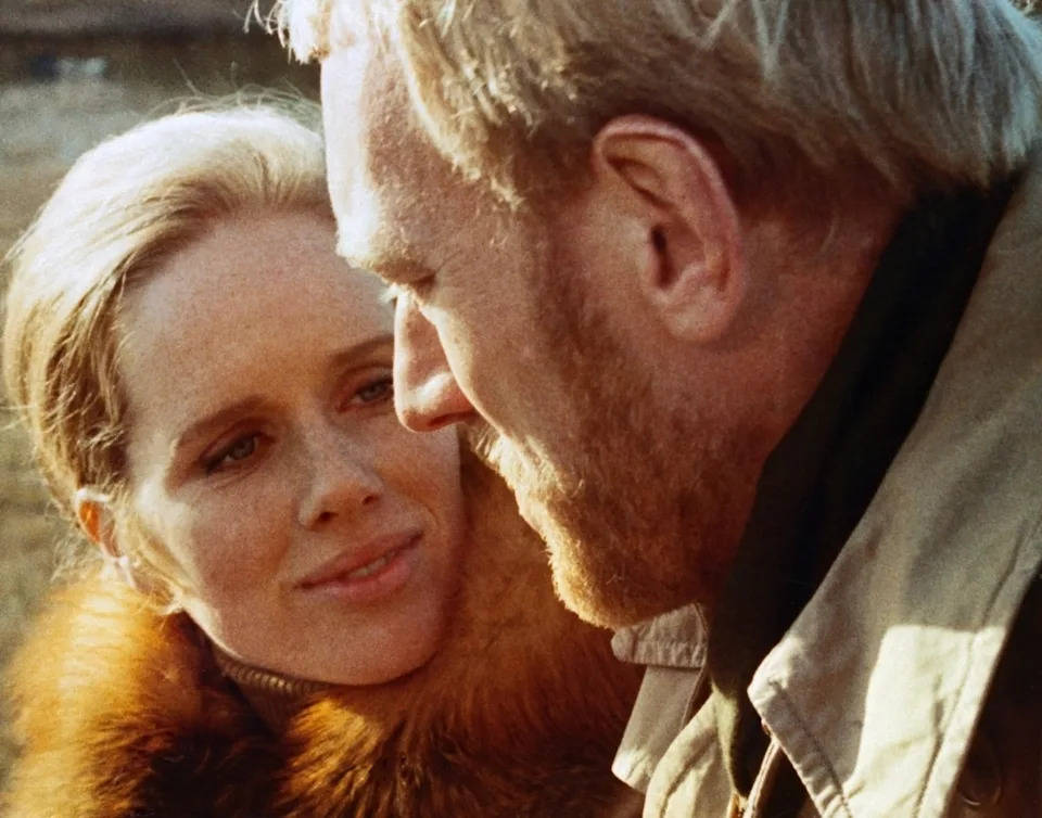 A woman and a man share a tender moment, smiling and close together, capturing an intimate interaction